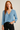 Woman wearing a blue patterned blouse against a plain background