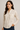 Woman wearing a beige button-up shirt against a plain background