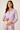 Woman wearing a light purple shirt with button details on a beige background
