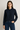 Woman wearing a navy blue shirt and jeans on a plain background