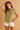 Woman wearing a yellow plaid shirt and white shorts on a beige background