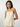 Woman wearing a beige sleeveless top with bow straps against a plain background