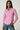 Woman wearing a pink and white checkered shirt with blue jeans on a plain background