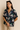 Woman wearing a dark floral shirt against a beige background