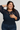 Woman wearing a navy blue blouse with sheer sleeves against a plain background