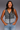 Woman wearing a patterned sleeveless top and jeans on a gray background