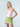 Woman wearing a pink top and green skirt against a light gray background