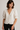 Woman wearing a white blouse with puff sleeves against a plain background