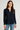 Woman wearing a navy blue shirt and light blue jeans on a plain background