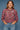 Woman wearing a floral blouse and jeans against a blue background