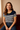 Woman wearing a striped shirt sitting on a couch with a neutral background