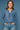 Woman wearing a blue floral blouse and jeans against a blue background