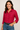Woman wearing a red shirt and blue jeans against a beige background