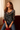 Woman wearing a floral long-sleeve top and jeans sitting on a red chair.