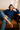 Woman sitting on a brown couch wearing a blue polka dot shirt and jeans.