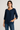 Woman wearing a navy blue blouse and jeans against a plain background