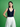 Woman wearing a navy tank top and white pants against a green background