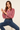 Woman wearing a red and white striped shirt and blue jeans sitting on a stool.