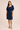 Woman wearing a navy blue dress on a beige background