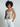 Woman wearing a floral camisole and white pants against a plain background