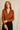 Woman wearing a brown blouse against a beige background