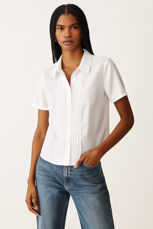 Woman wearing a white short-sleeve blouse and blue jeans on a plain background