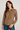 Woman wearing a brown and white striped shirt with blue jeans on a plain background